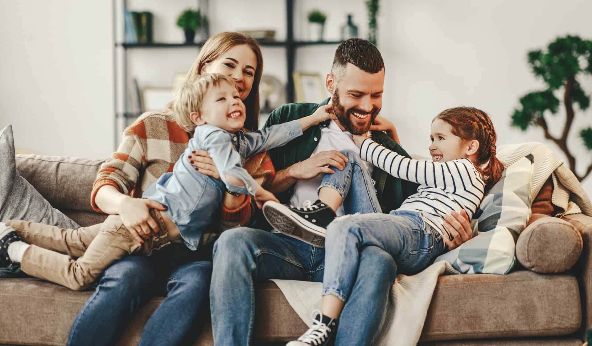 happy family mother father and kids at home on couch