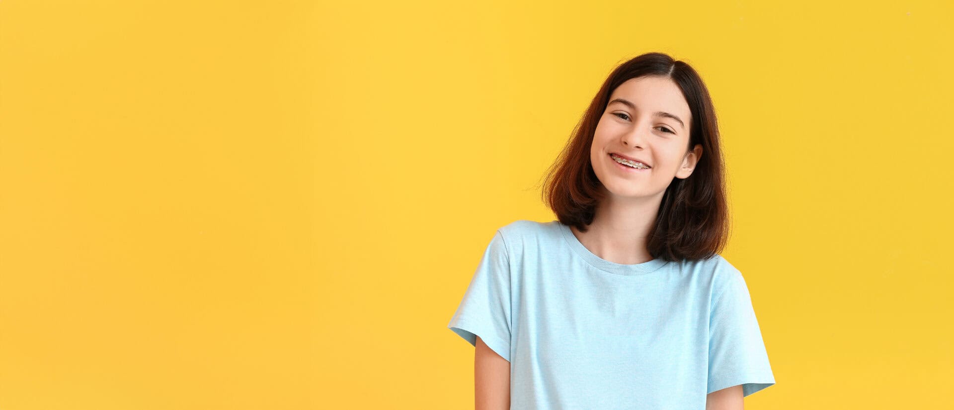 Teenage girl with dental braces on color background